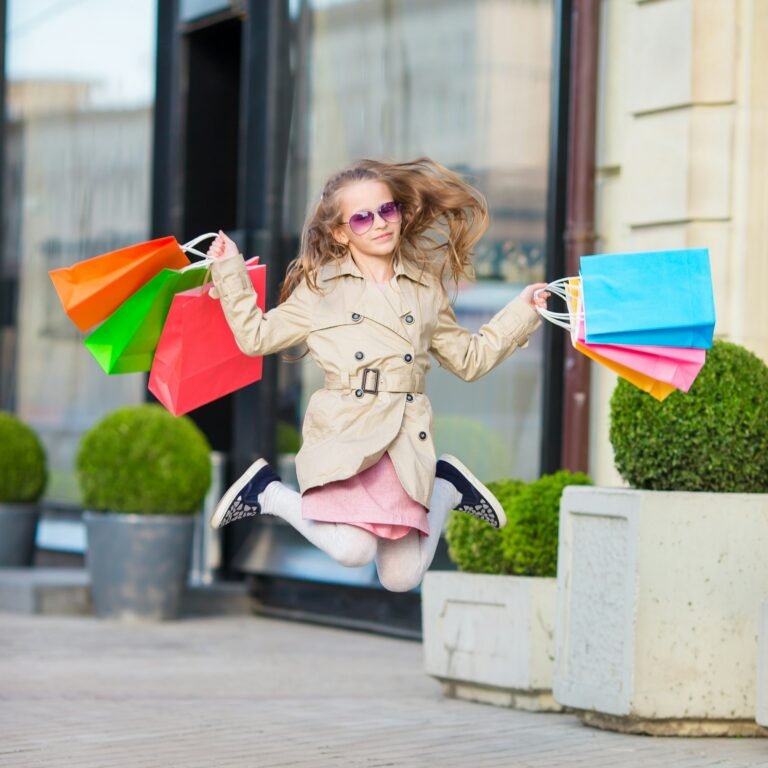 Adorable little girl walking with shopping bags outdoors in Europe. Fashion toddler kid in european