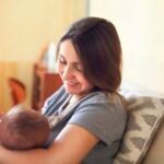Young mother holding her newborn child. Mom nursing baby.