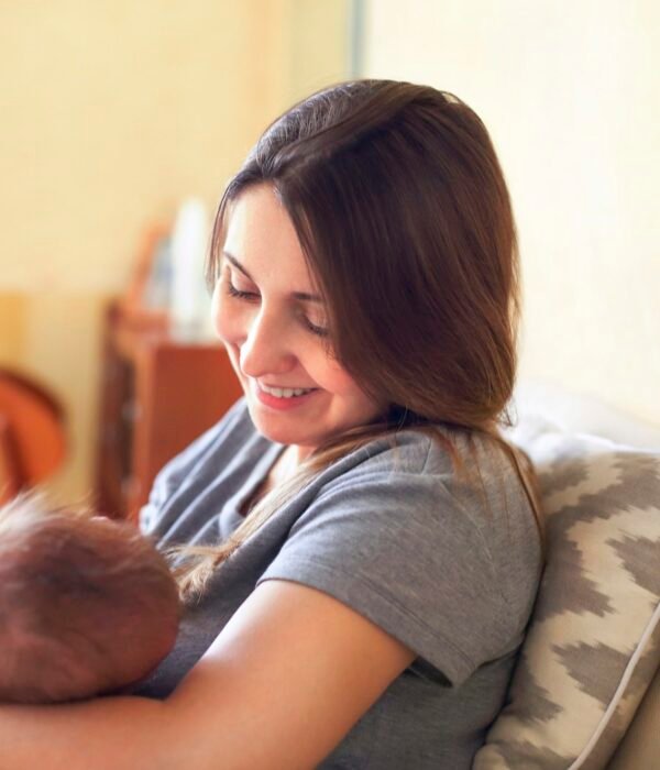 Young mother holding her newborn child. Mom nursing baby.